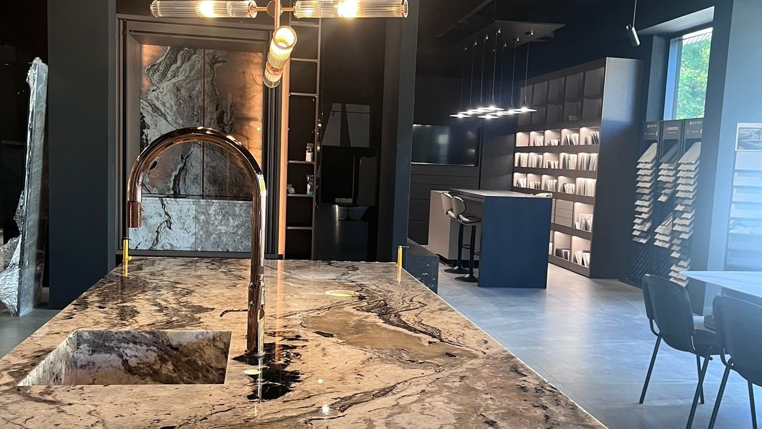 Wyspa kuchenna z kwarcytu w showroomie GRES DESIGN w Częstochowie, w tle podświetlana ekspozycja płyt wielkoformatowych